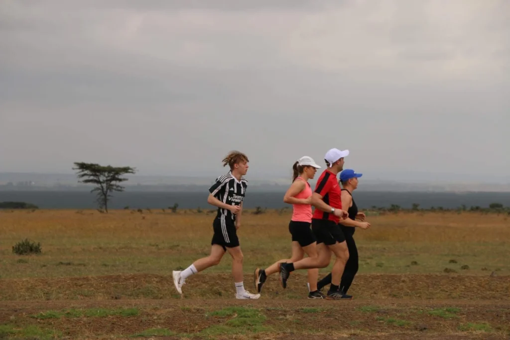 Eesti turistid jooksevad Keenia savannimaastikul lagedal tasandikul akaatsiapuudega taustal